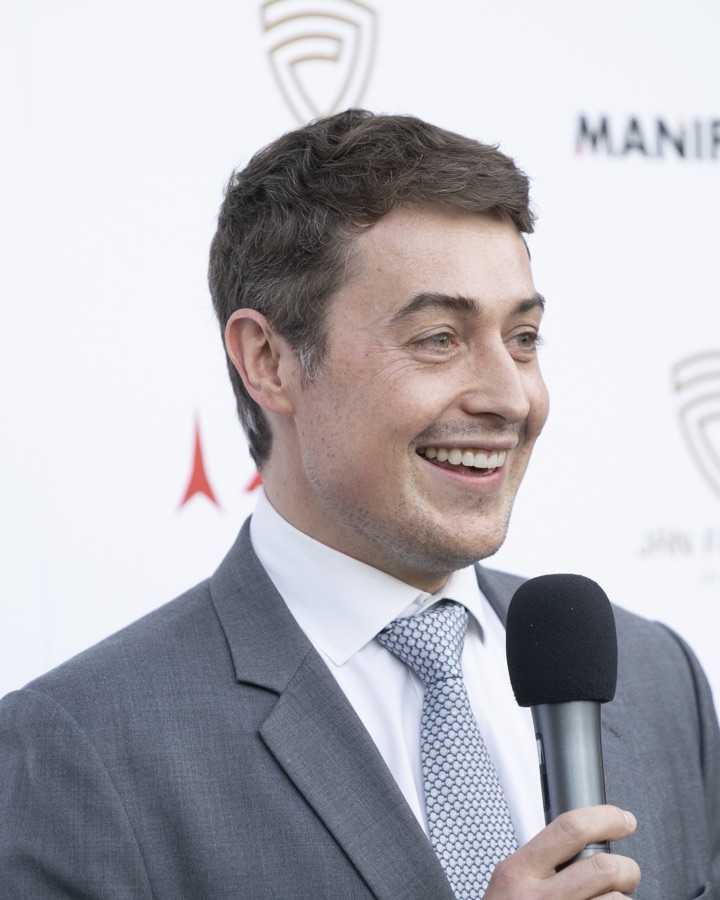 Jan Farrell in a grey suit, speaking at an event